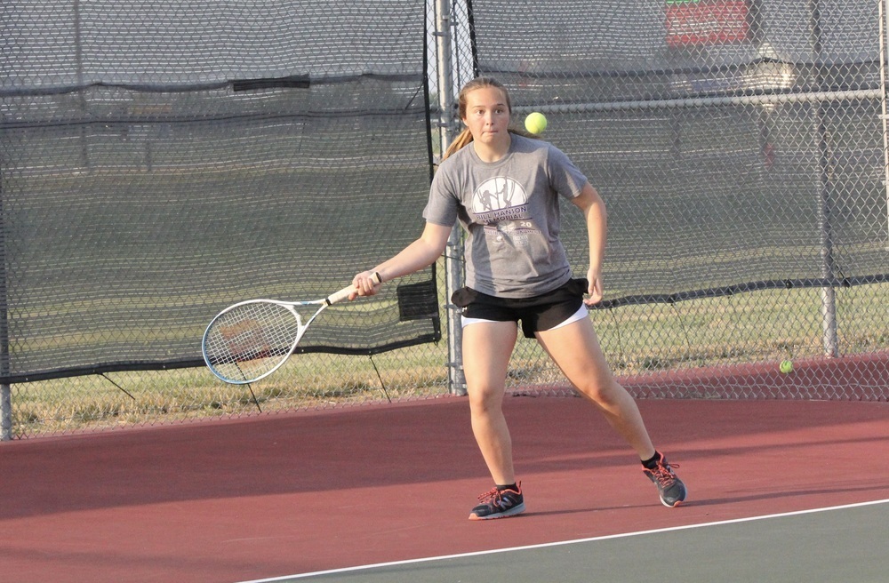 A girl strikes a tennis ball with a racquet